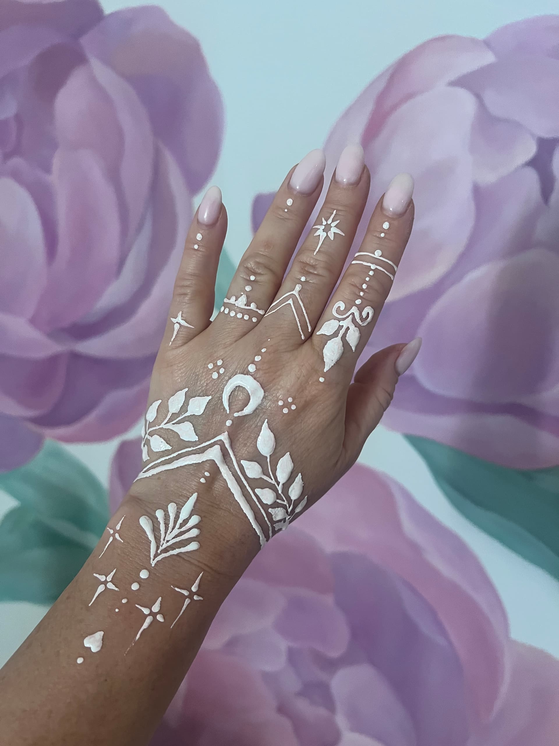 White henna lace pattern covering the back of a hand and wrist