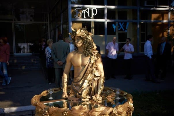 Golden living table performer draped in fabric on a mirrored tabletop